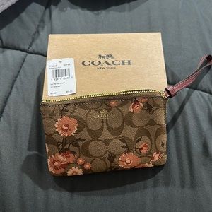 Coach Wristlet with tan/brown coach logo and peach/pink flowers.
